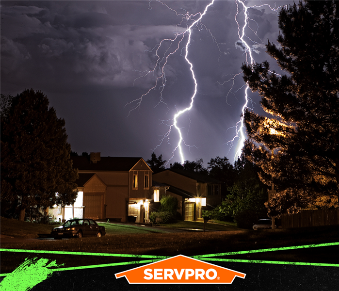 Lighting in the sky over a neighborhood with the SERVPRO logo.
