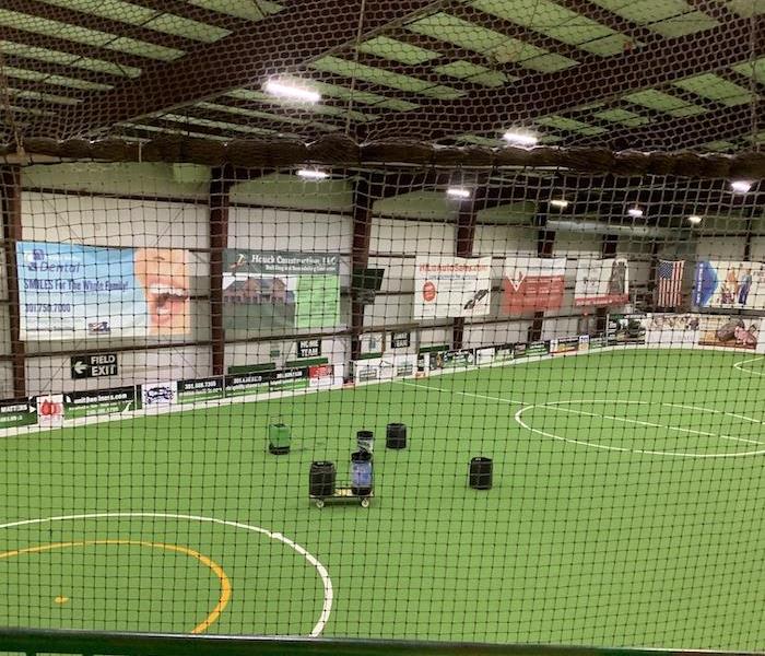 Indoor soccer field with SERVPRO drying equipment on the turf