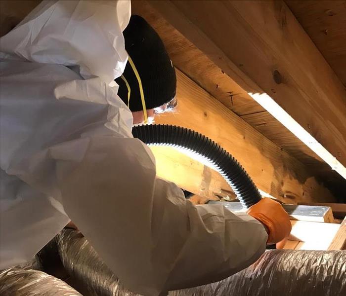 SERVPRO employee working in an attic removing soot