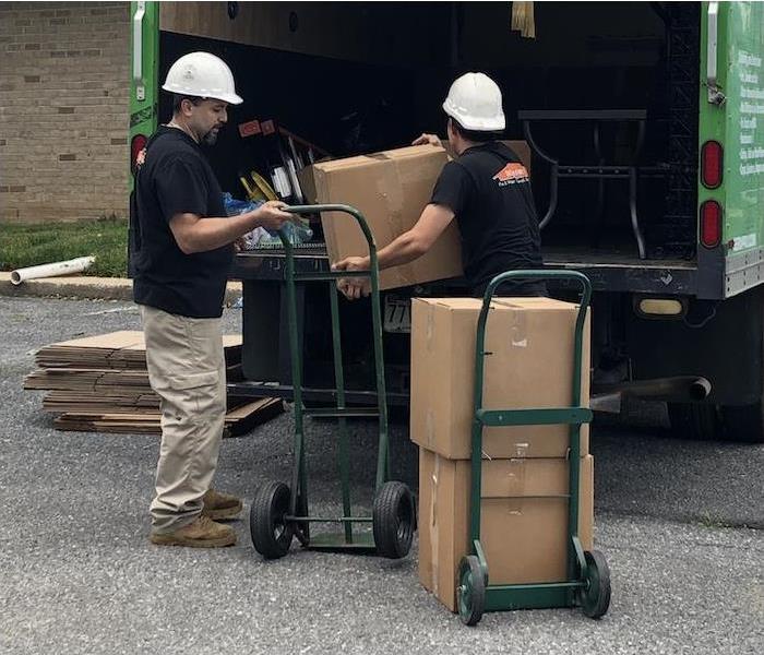 Two SERVPRO technicians moving boxes from a fire damaged house into a truck