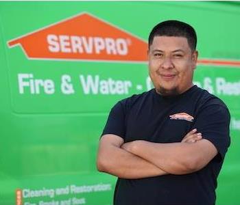 Man in mid-thirties with short, neatly trimmed, dark hair and chin beard in SERVPRO T-shirt, standing next to a SERVPRO truck